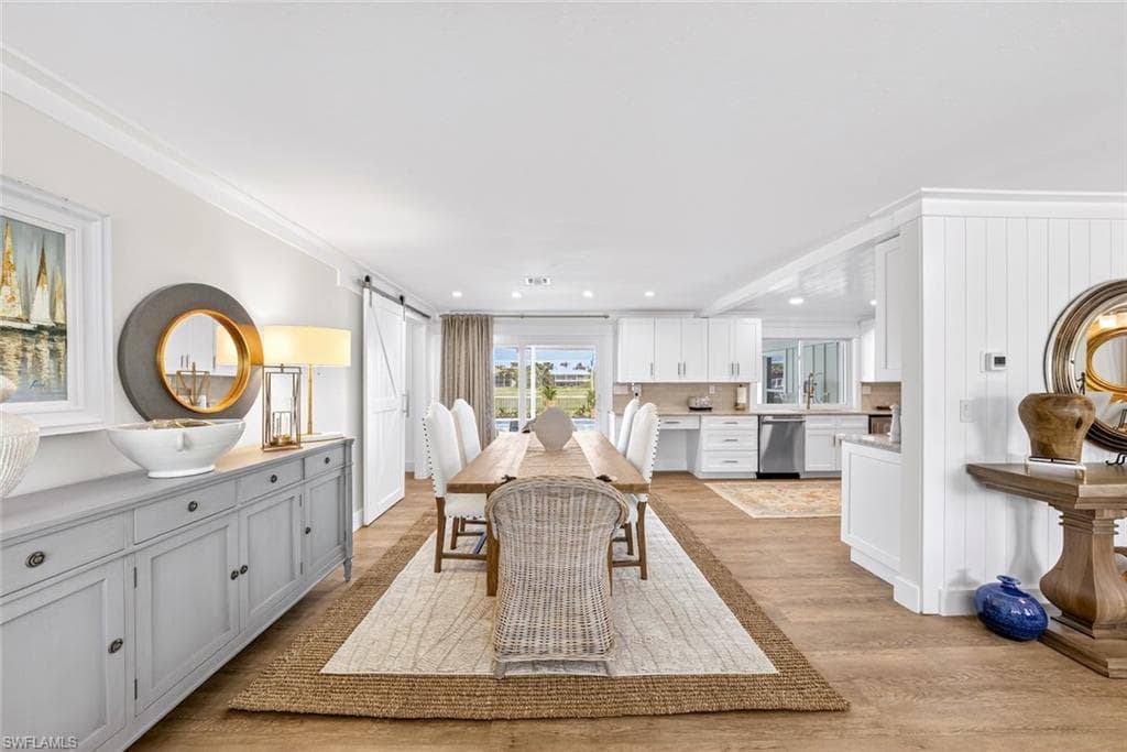 Open-concept dining area featuring wood-finish flooring, a long dining table, and a sliding barn door