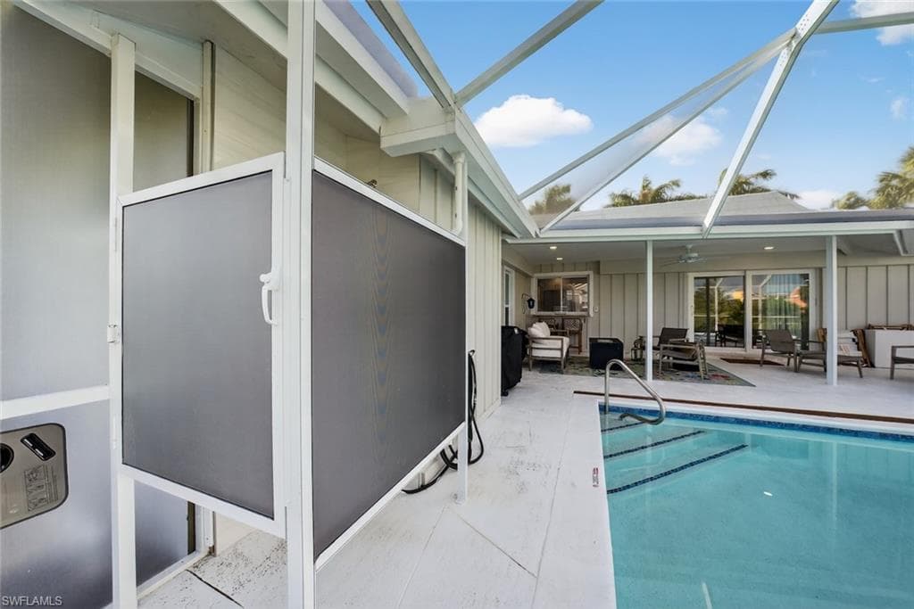 Screened lanai featuring a swimming pool with integrated steps, a covered patio area, and sliding glass doors leading into the residence