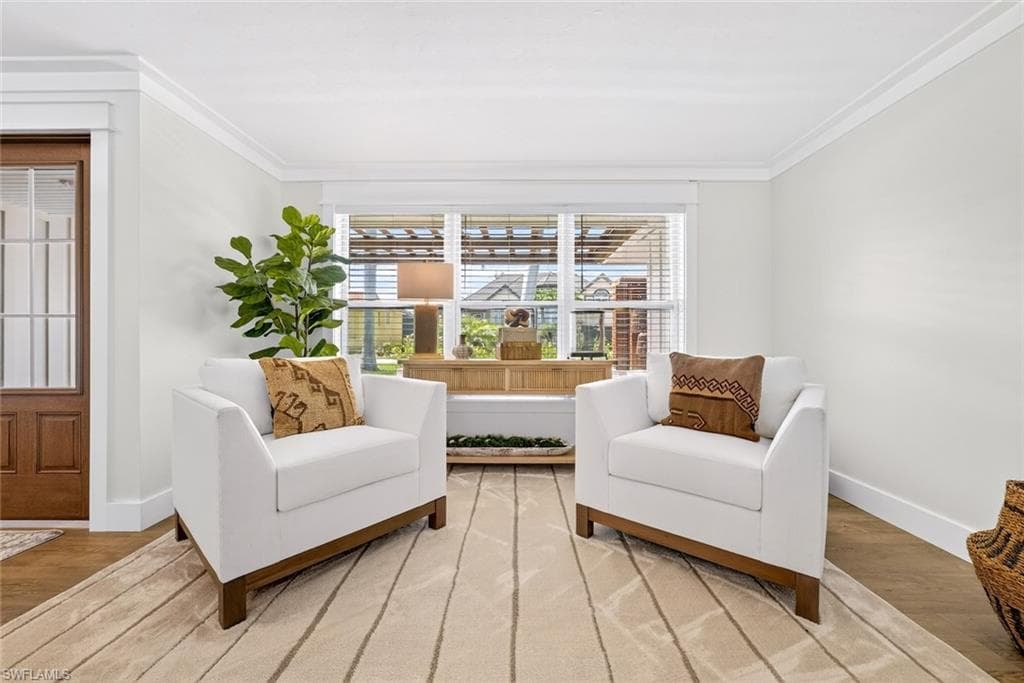 Light-filled room featuring a large window, crown molding, and wood-finish flooring