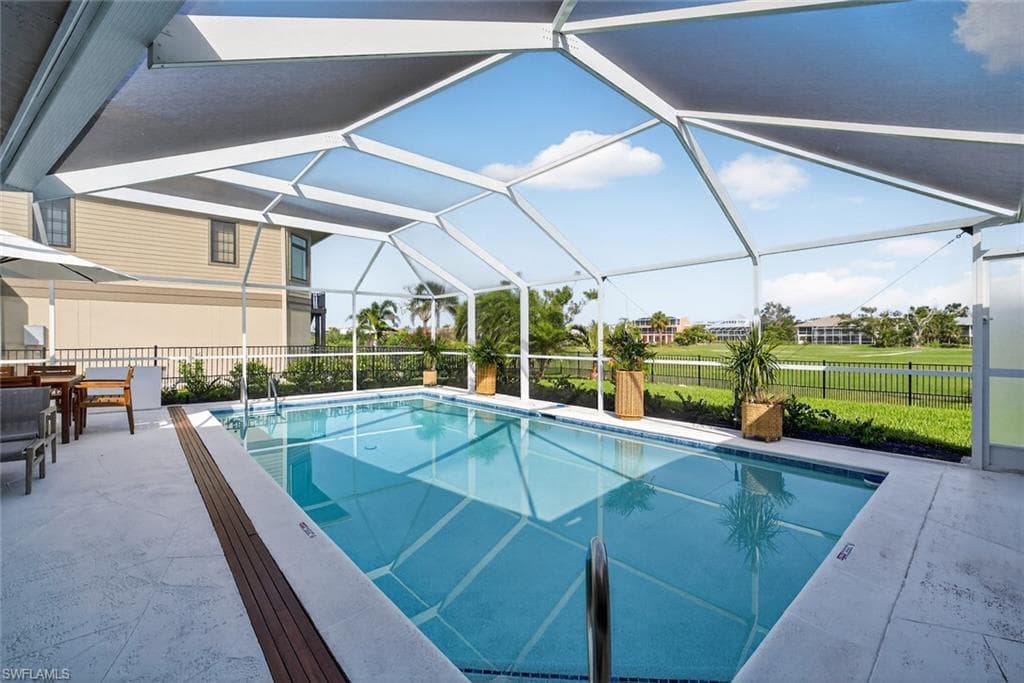 Screened pool enclosure featuring a rectangular pool with integrated steps, concrete paver decking, and a wood-finish plank accent border