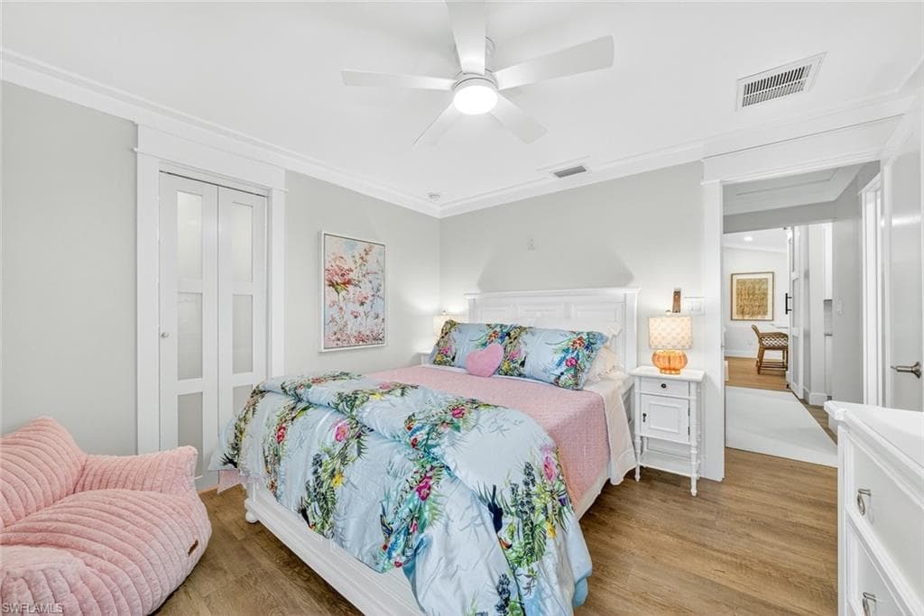 Bedroom featuring wood-finish flooring and a white ceiling fan with integrated lighting