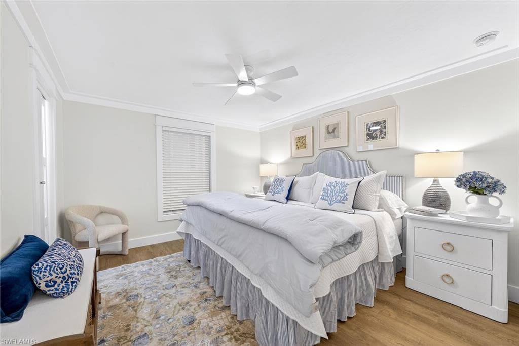 Spacious room featuring wood-finish flooring, a ceiling fan, crown molding, a window with blinds, and painted walls