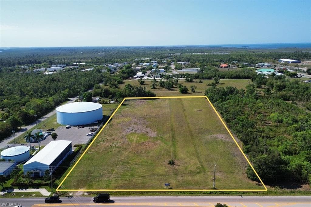 Expansive cleared lot outlined in yellow, featuring direct frontage on a paved roadway