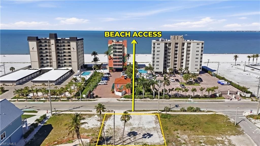 Vacant land parcel featuring mature palm trees and direct beach access across the street