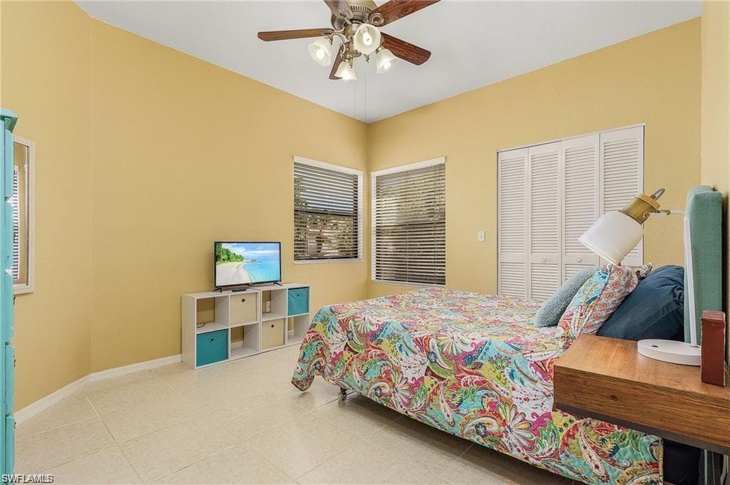 Bedroom with tile patterned flooring, a closet, a ceiling fan, and baseboards