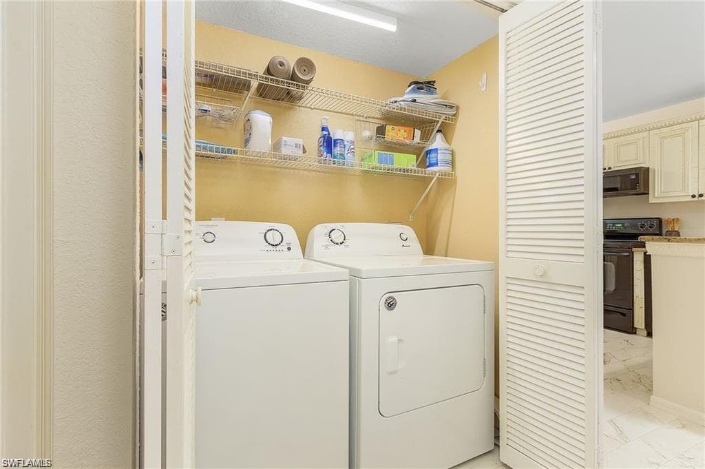 Laundry room with washer and dryer, laundry area, and marble finish floor