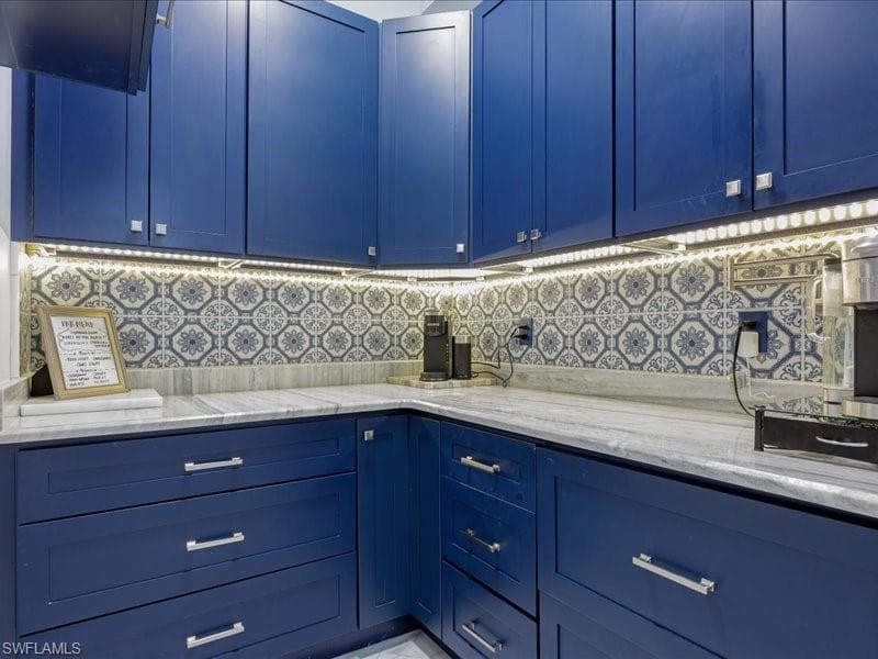 Butler's Pantry - Custom navy cabinetry with brushed nickel hardware, patterned tile backsplash, under-cabinet lighting, and light-toned countertops