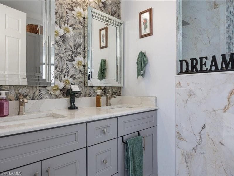 Double vanity with light gray shaker cabinetry, dual undermount sinks, and brushed nickel hardware