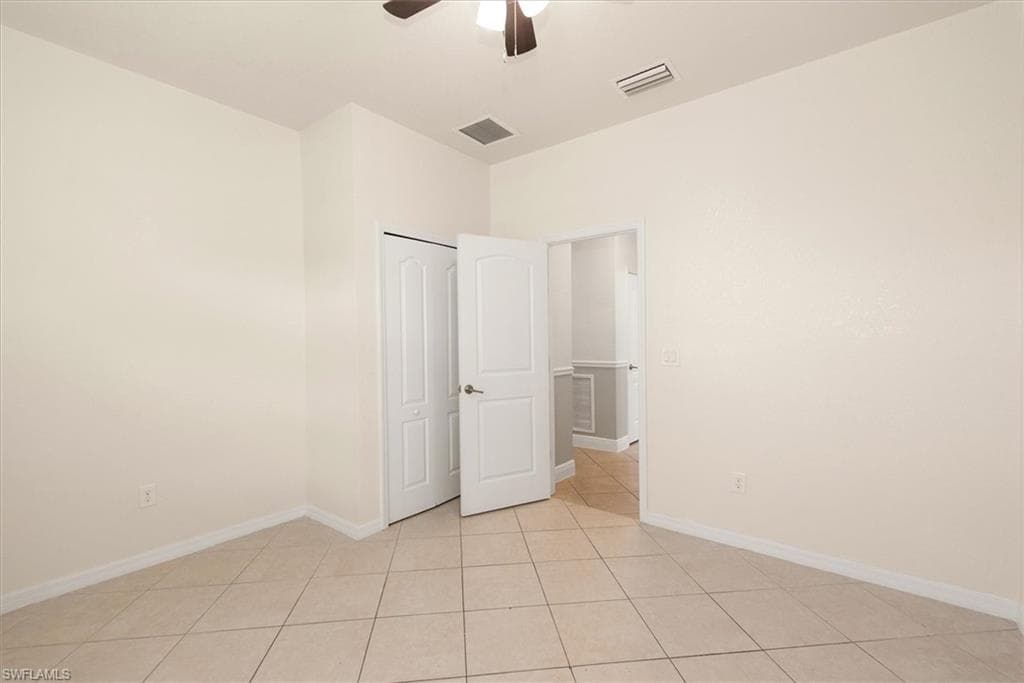 Original view of bedroom 2 with tile flooring, neutral finishes, and ceiling fan.