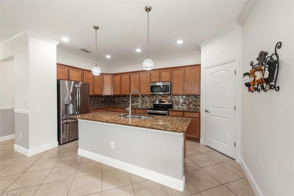 Kitchen with stainless steel appliances, tile backsplash, recessed lighting, and tile flooring.