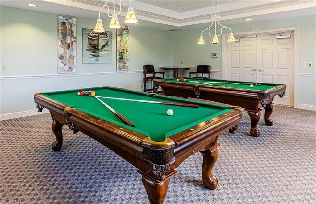 Community recreation room with billiards tables, patterned carpet, and decorative ceiling detail.
