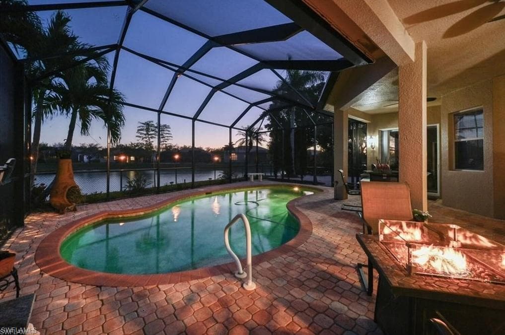 Screened-in lanai featuring a covered patio with a ceiling fan, a brick paver deck, a swimming pool, and a water feature