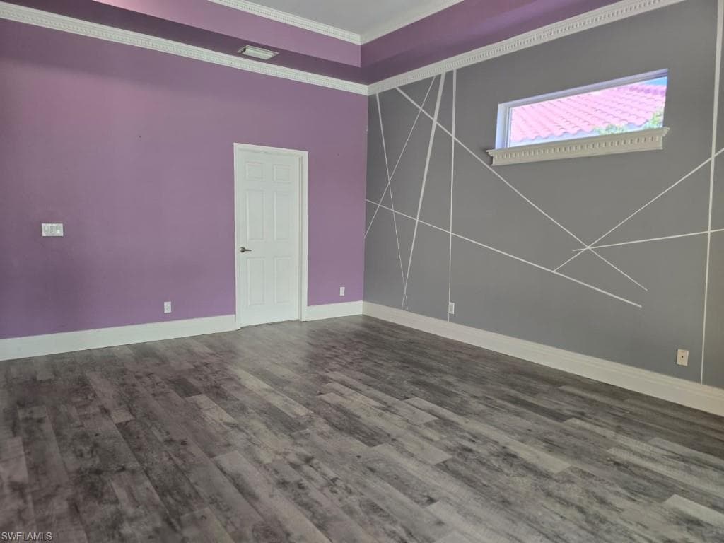 Room featuring wood-finish flooring, crown molding, and a vaulted ceiling