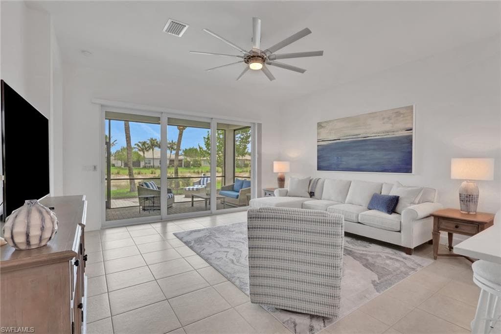 Spacious living area featuring large sliding glass doors opening to a screened lanai with outdoor seating