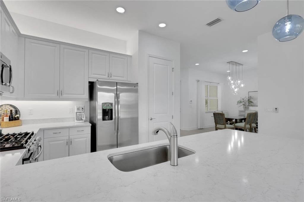 Kitchen featuring stainless steel appliances, light gray cabinetry, and light-toned countertops