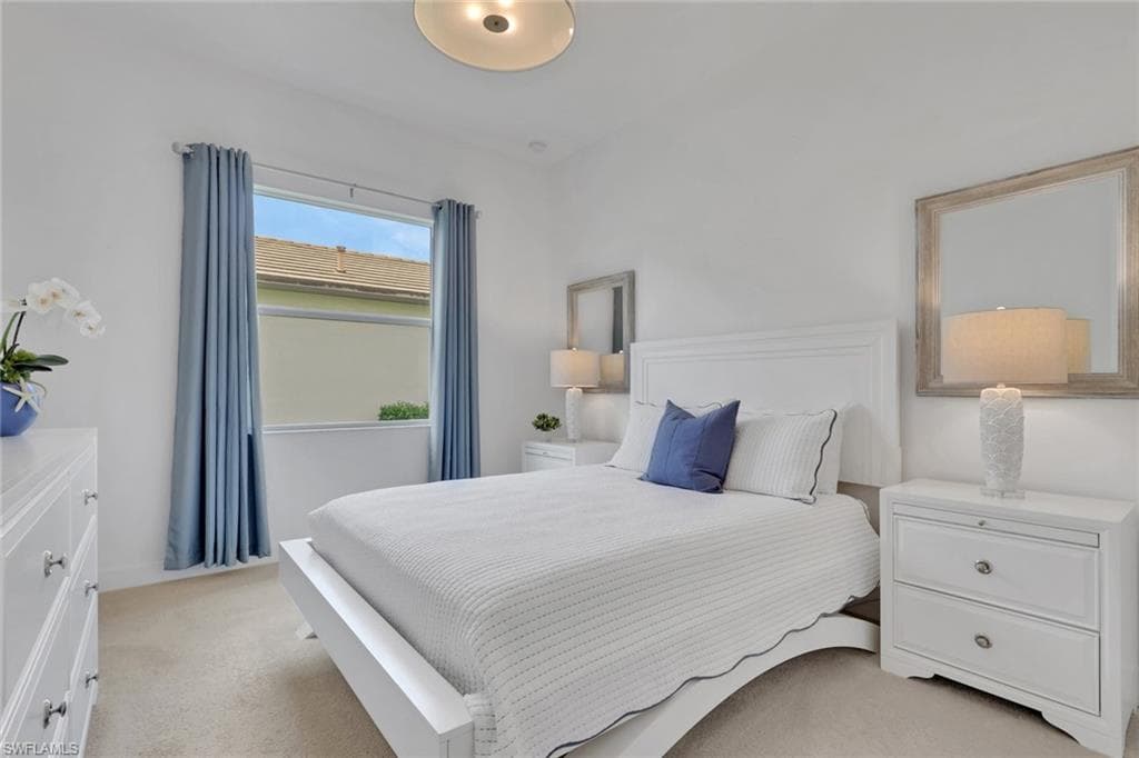 Bright room featuring light neutral carpeting, white walls, and a large window with blue drapery