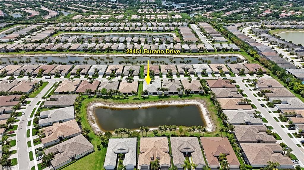 Aerial perspective of a residential community featuring a property with a water-facing backyard and surrounding homes with varied rooflines