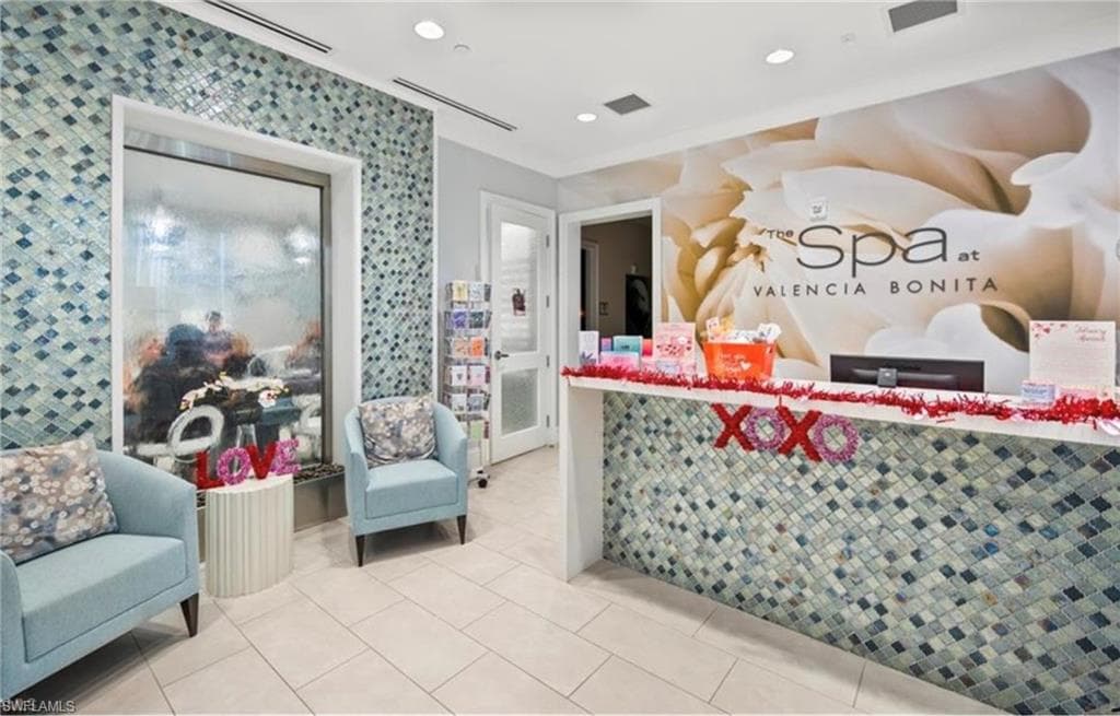 Spa reception area featuring a tiled accent wall and a built-in water feature