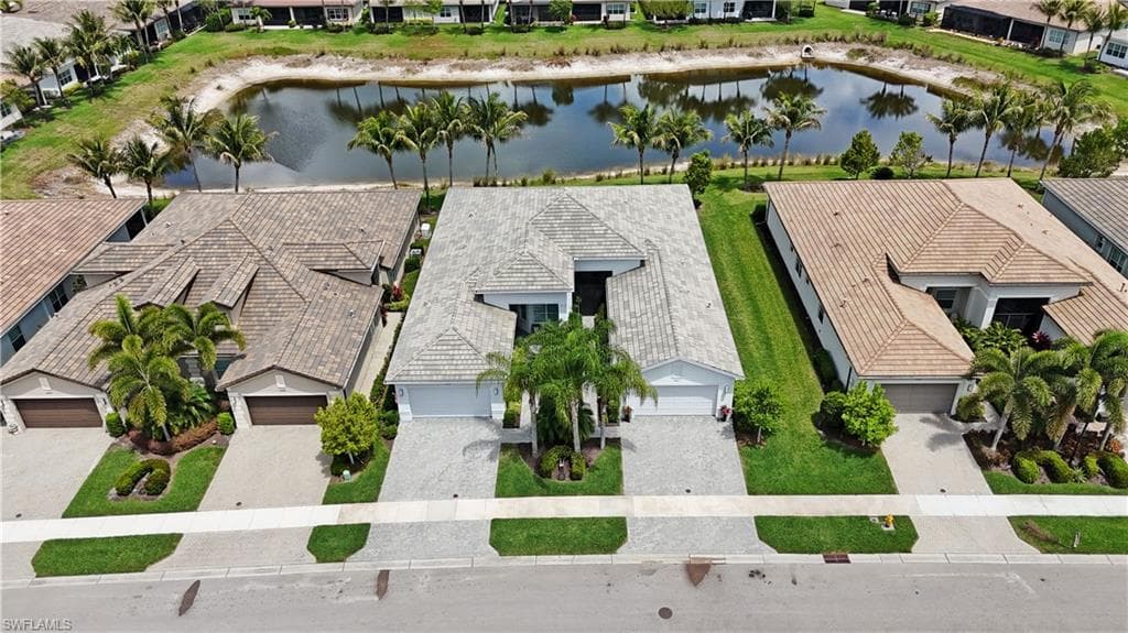 Aerial perspective showcasing a property with a tile roof, paver driveway, and mature landscaping