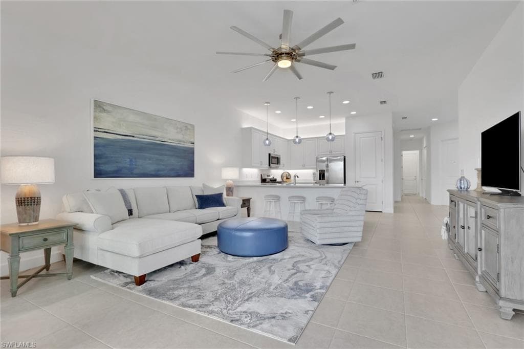 Open-concept living area featuring light-toned tile flooring, recessed lighting, and a contemporary ceiling fan