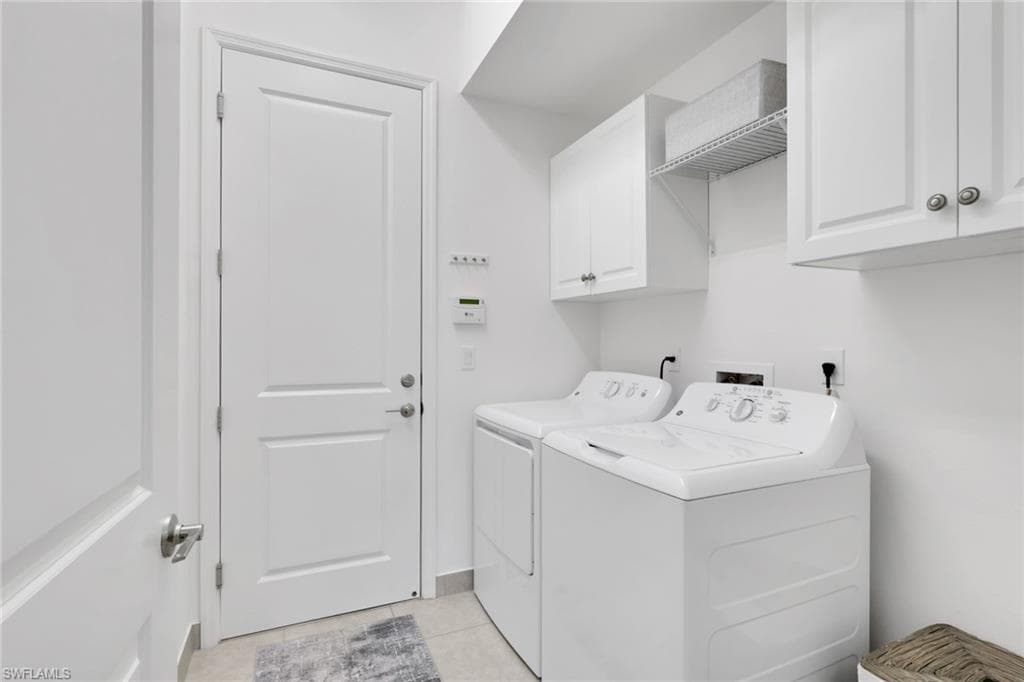 Dedicated laundry area featuring white cabinetry, an open wire shelf, and light-toned tile flooring