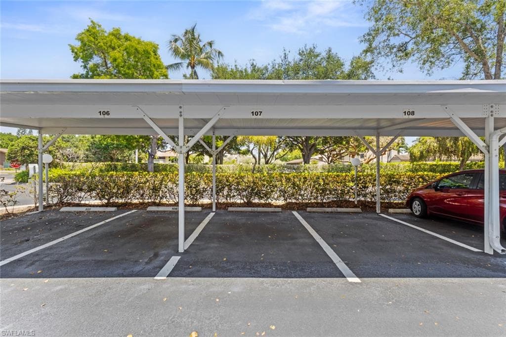 Assigned covered parking featuring numbered space #107, a white metal car port structure, and mature landscaping