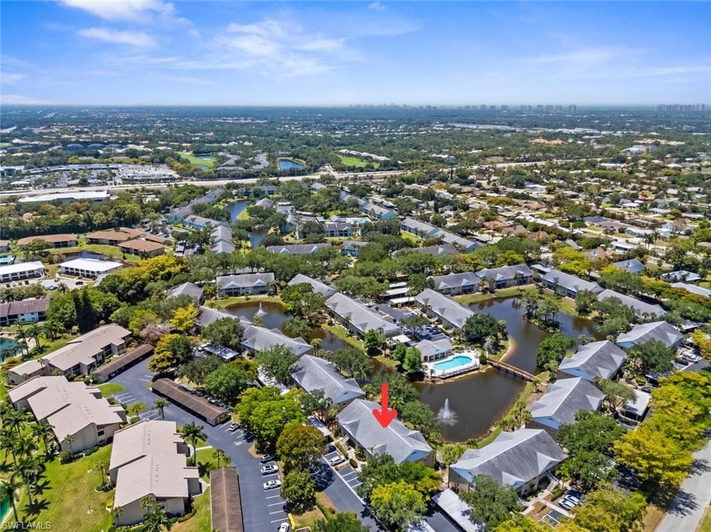 Aerial overview of a community featuring multiple residential buildings surrounding a central pond with a fountain