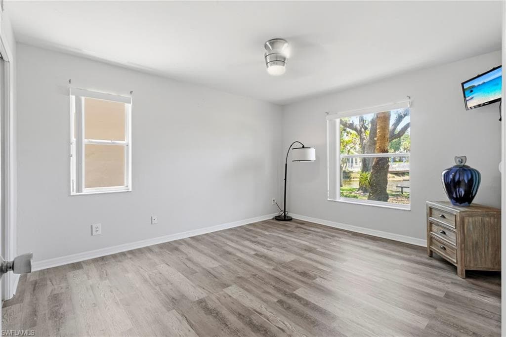 Spacious interior room featuring wood-finish flooring, light gray wall paint, and white trim