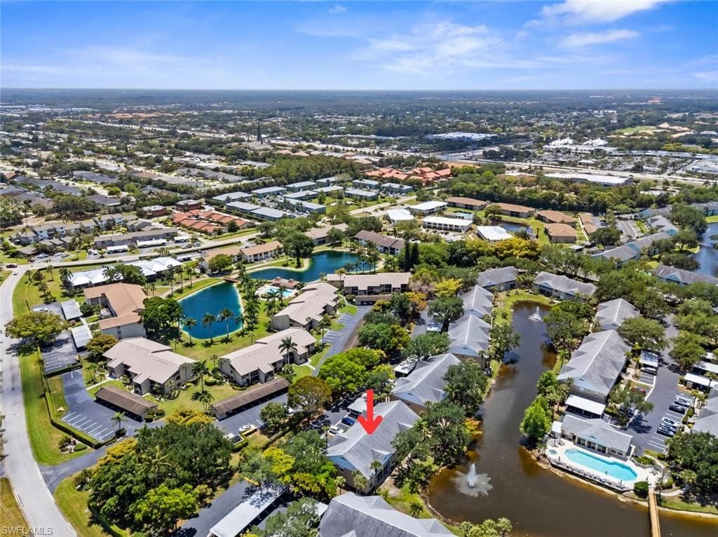 Aerial perspective showcasing a community with multiple residential buildings, surrounded by mature trees and lush landscaping