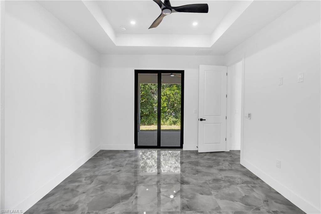 Spacious interior with high tray ceilings, recessed lighting, wood-finish flooring, and a contemporary ceiling fan