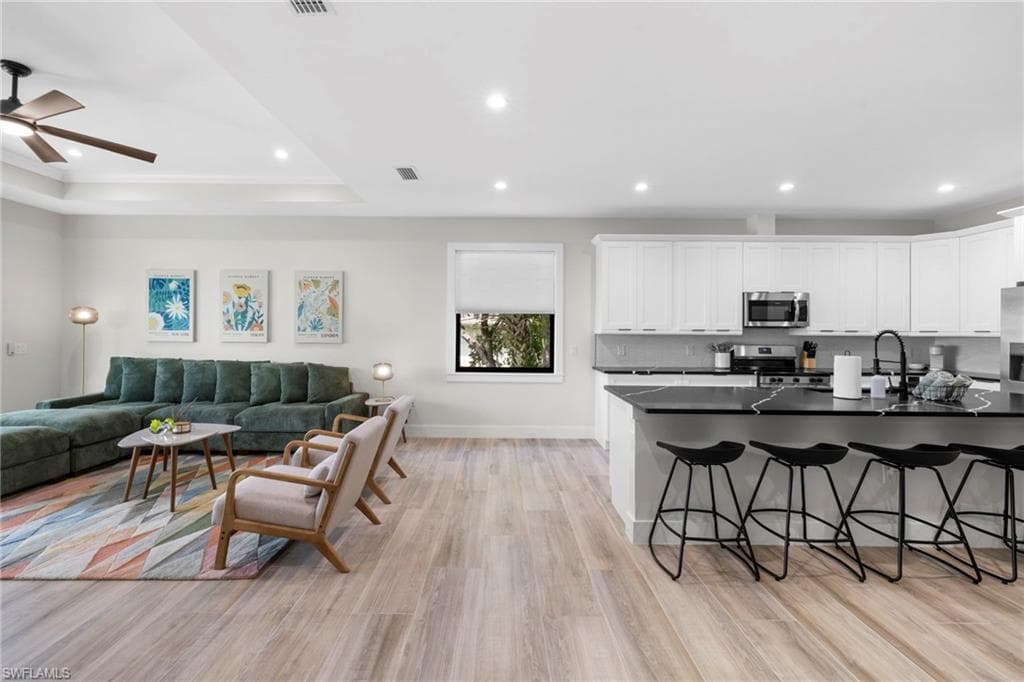 Open-concept living space featuring wood-finish flooring, recessed lighting, and a tray ceiling