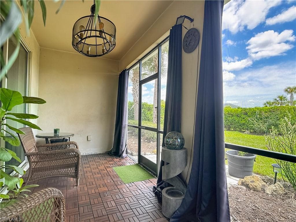 Screened-in patio featuring wood-finish flooring, an overhead light fixture, and a lush green landscape beyond