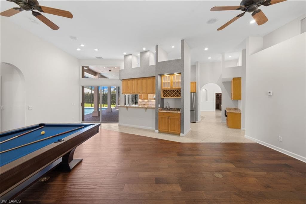 Spacious room featuring rich wood-finish flooring, high vaulted ceilings, and recessed lighting