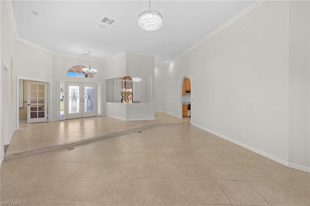 Spacious living area featuring high ceilings, crown molding, and large format tile flooring