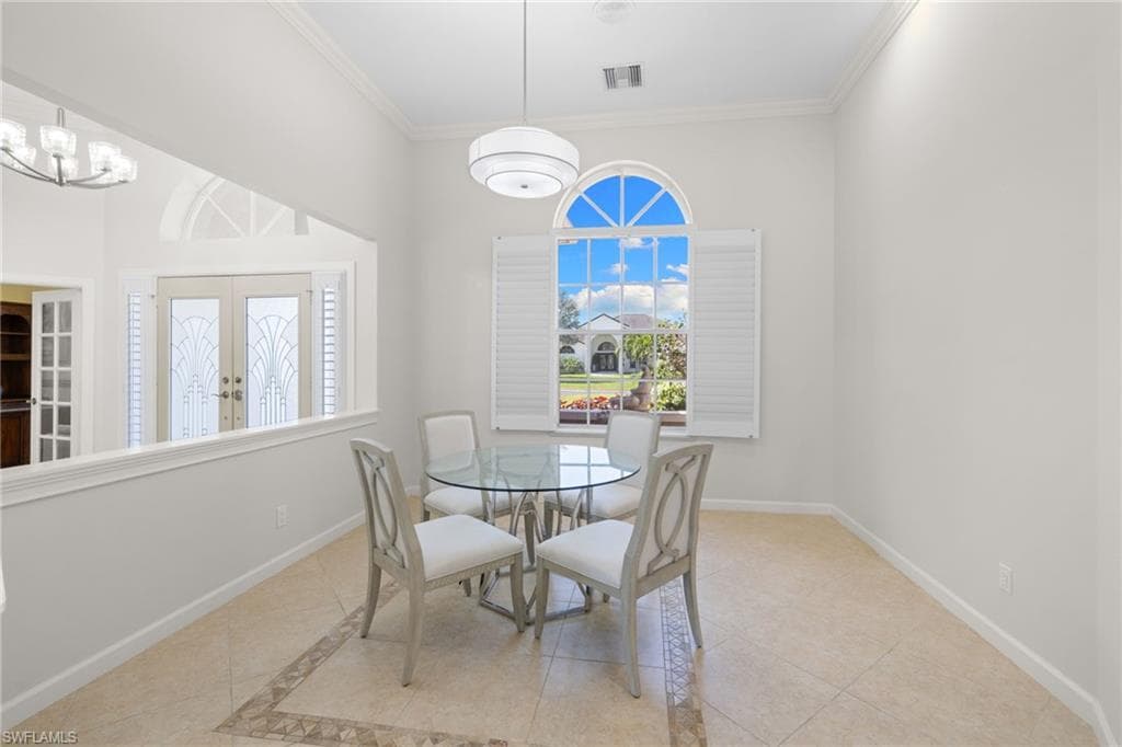 Bright interior with tiled flooring featuring an accent border, high ceilings with crown molding, and an arched wall niche