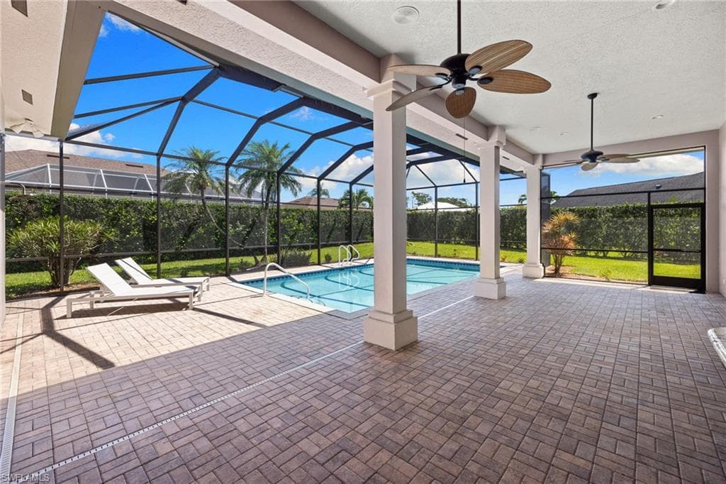 Screened-in pool area featuring a rectangular swimming pool with integrated steps, surrounded by a paver deck