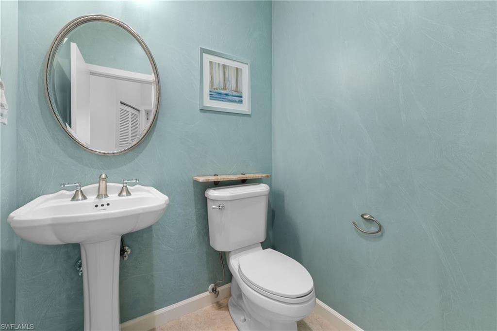 Den/office featuring a large arched window with white plantation shutters, vaulted ceiling, crown molding, and tiled flooring