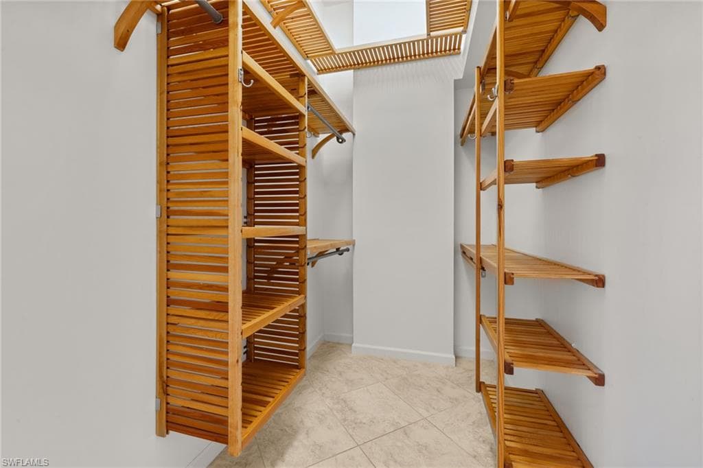 Primary bedroom #1, spacious interior featuring a light-toned tile floor, vaulted ceiling, and ceiling fan