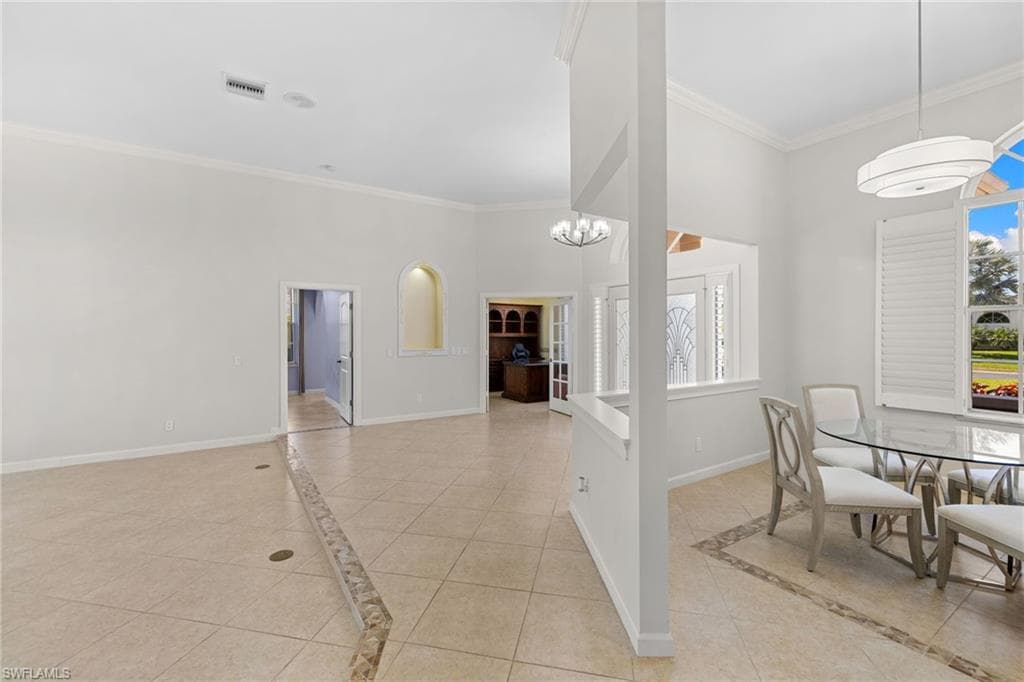 Spacious interior featuring tile flooring with decorative inlay, French doors, transom window, and crown molding