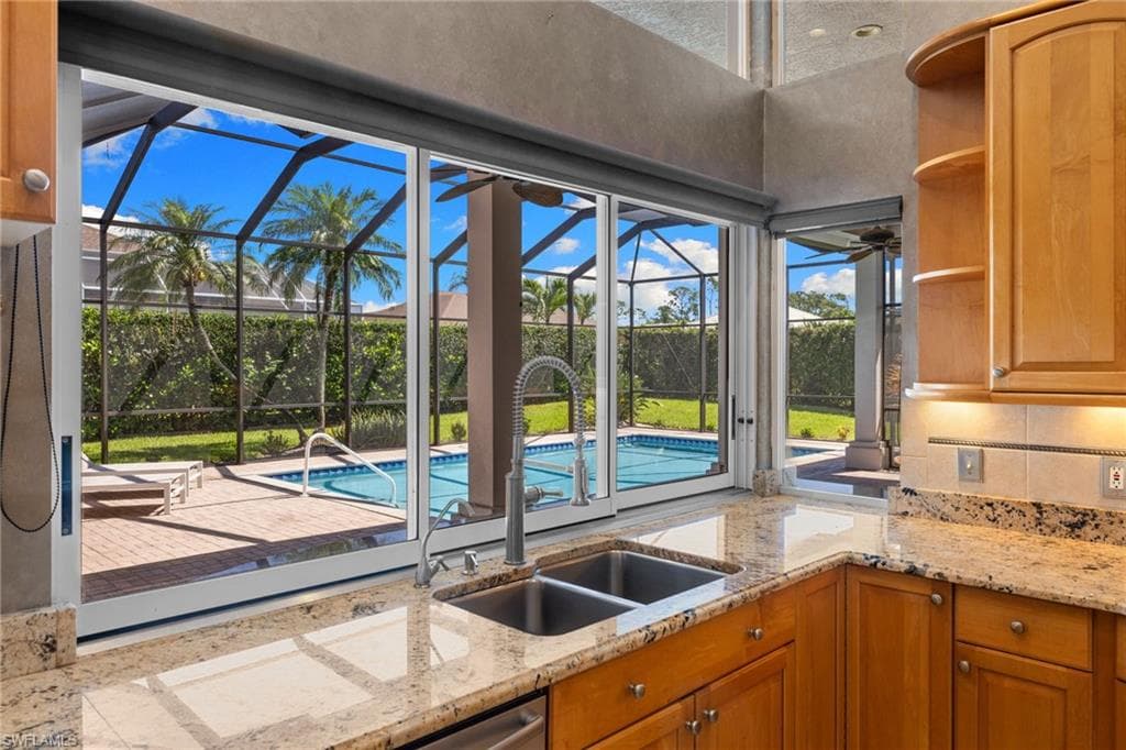 Dining area featuring a large arched window with plantation shutters, a contemporary pendant light fixture, and tile flooring with decorative inlay