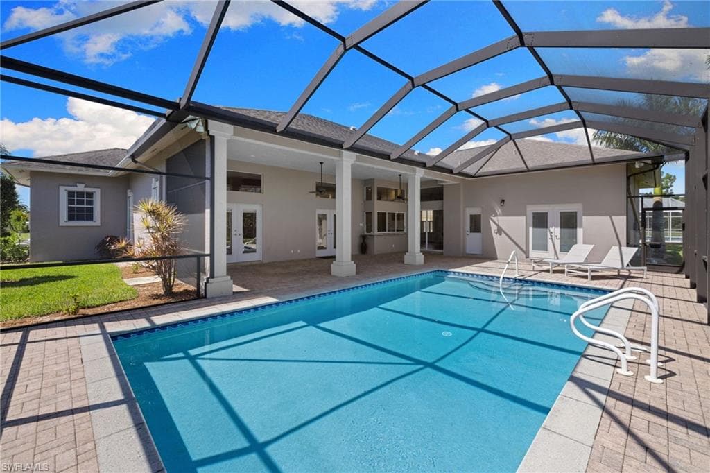 Screened-in outdoor living space featuring an in-ground swimming pool, brick paver patio, and multiple ceiling fans