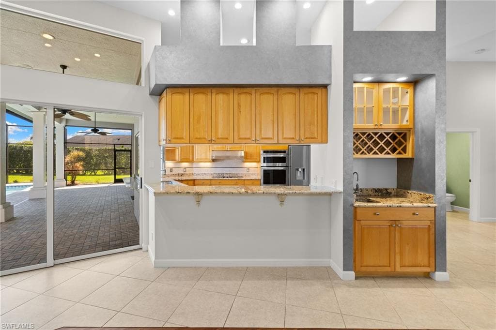 Spacious room with wood-finish flooring and high ceilings, featuring a built-in wet bar with wood cabinetry and a wine rack
