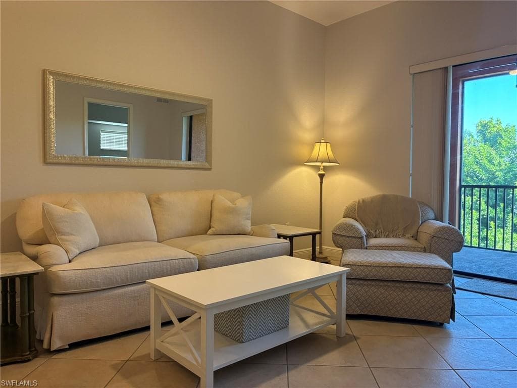 Spacious living area featuring neutral wall tones, tile flooring, and direct access to an outdoor balcony