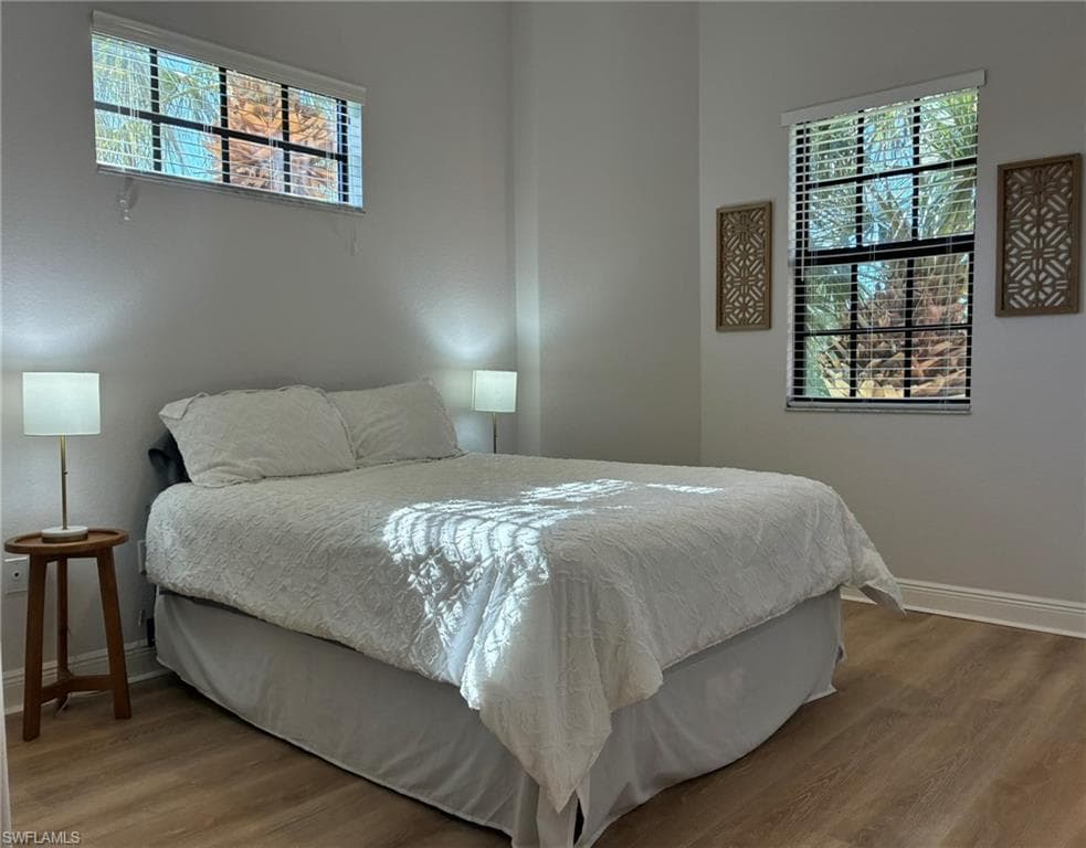 Light-filled interior featuring wood-finish flooring, white baseboards, and two windows with blinds