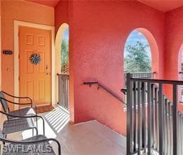 Exterior entry with a paneled door, arched openings, a dark metal railing, and a handrail