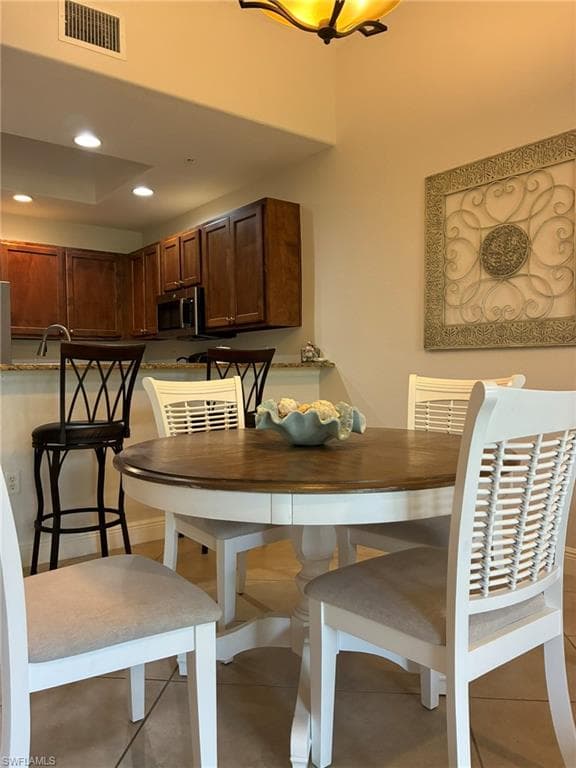Kitchen and dining area featuring warm wood cabinetry, a granite countertop peninsula, and recessed lighting