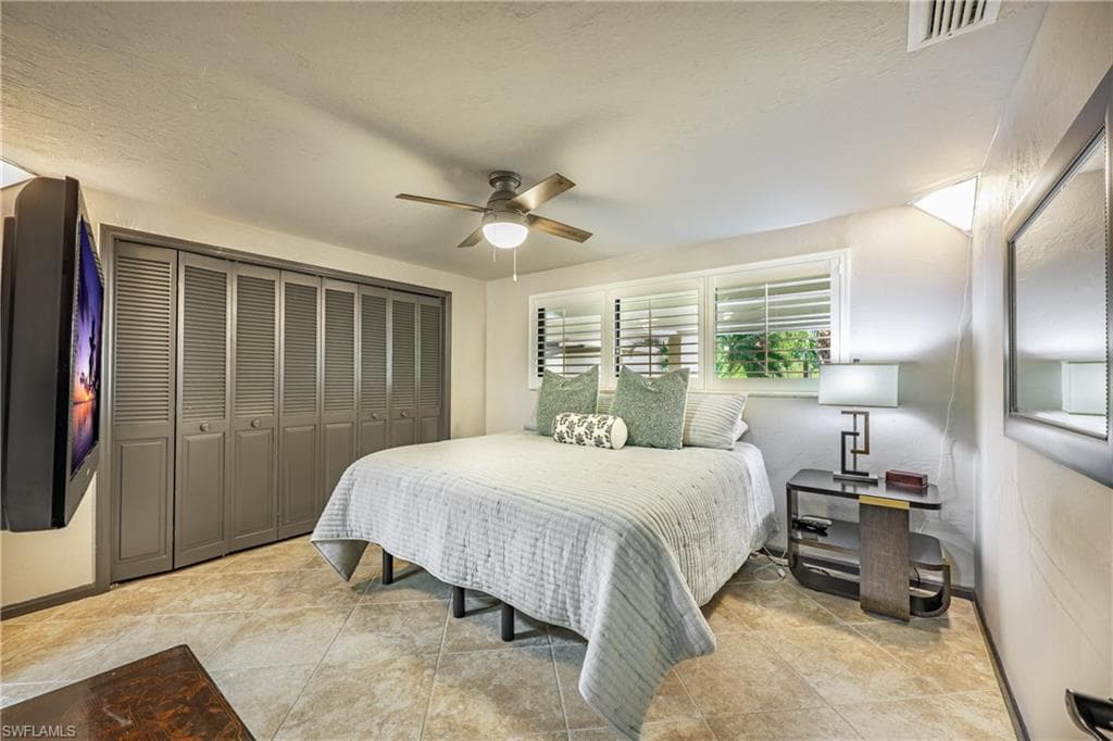 Spacious room featuring tile flooring, bi-fold louvered closet doors, window shutters, and a ceiling fan with integrated lighting