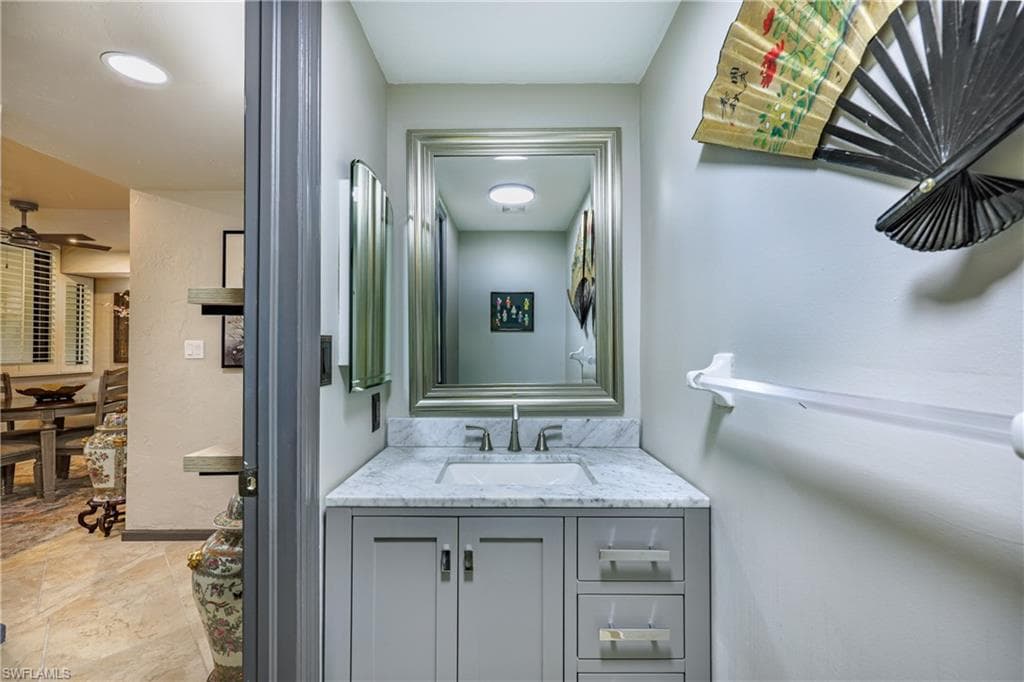 Bathroom vanity featuring a light gray cabinet with brushed nickel hardware, an integrated rectangular sink, and a stone countertop