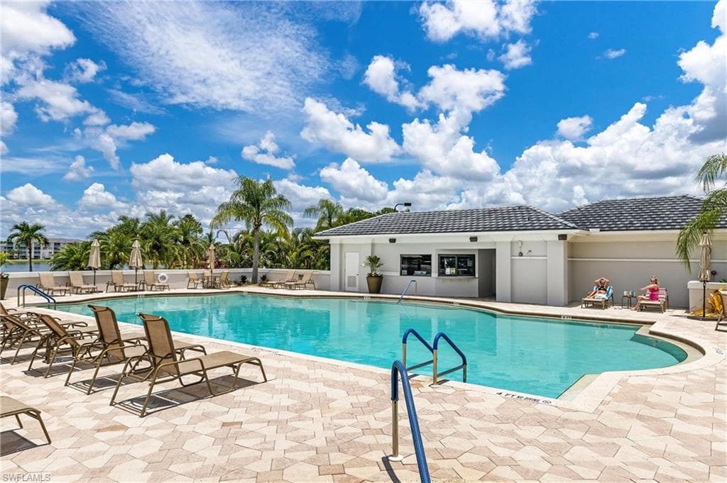 Expansive outdoor pool area with a curvilinear swimming pool, surrounded by patterned paver decking