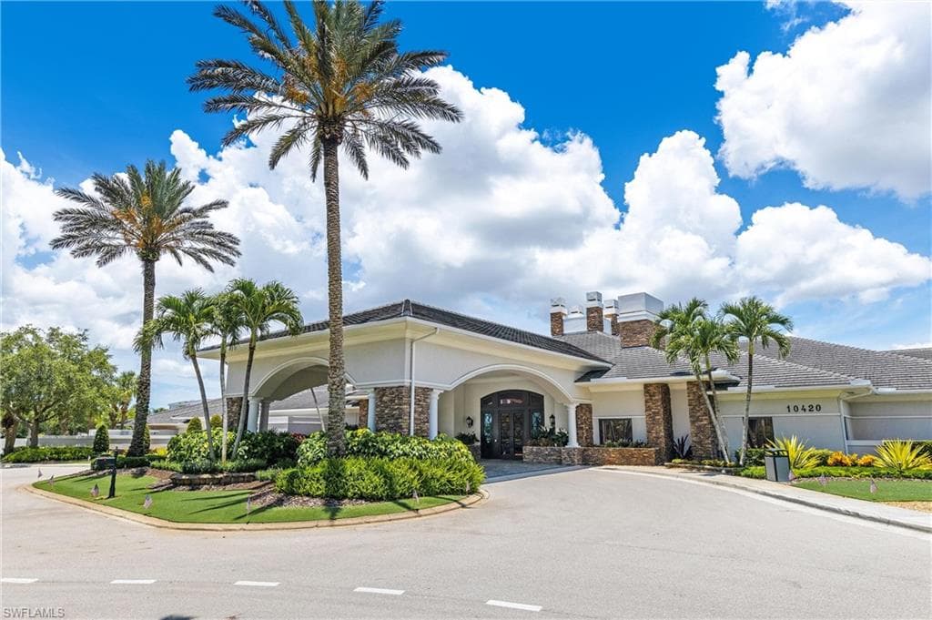 Stately clubhousebuilding exterior featuring a covered porte-cochère entrance, stone facade accents, and a tile roof